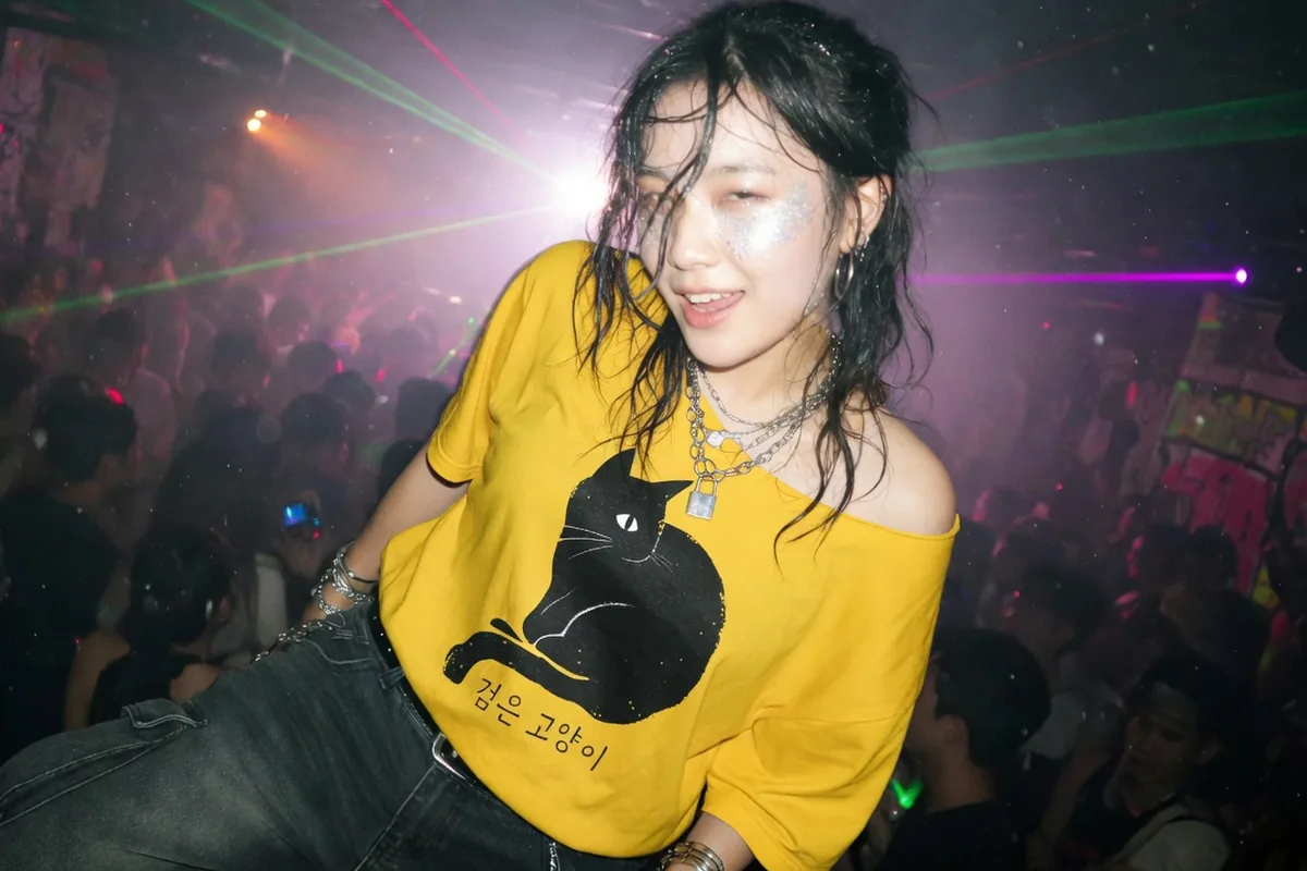 Woman in a club wearing the StyleMZ Black Cat yellow graphic tee